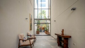 Un couloir avec un coin salon, une table en bois et une vue sur l’extérieur.