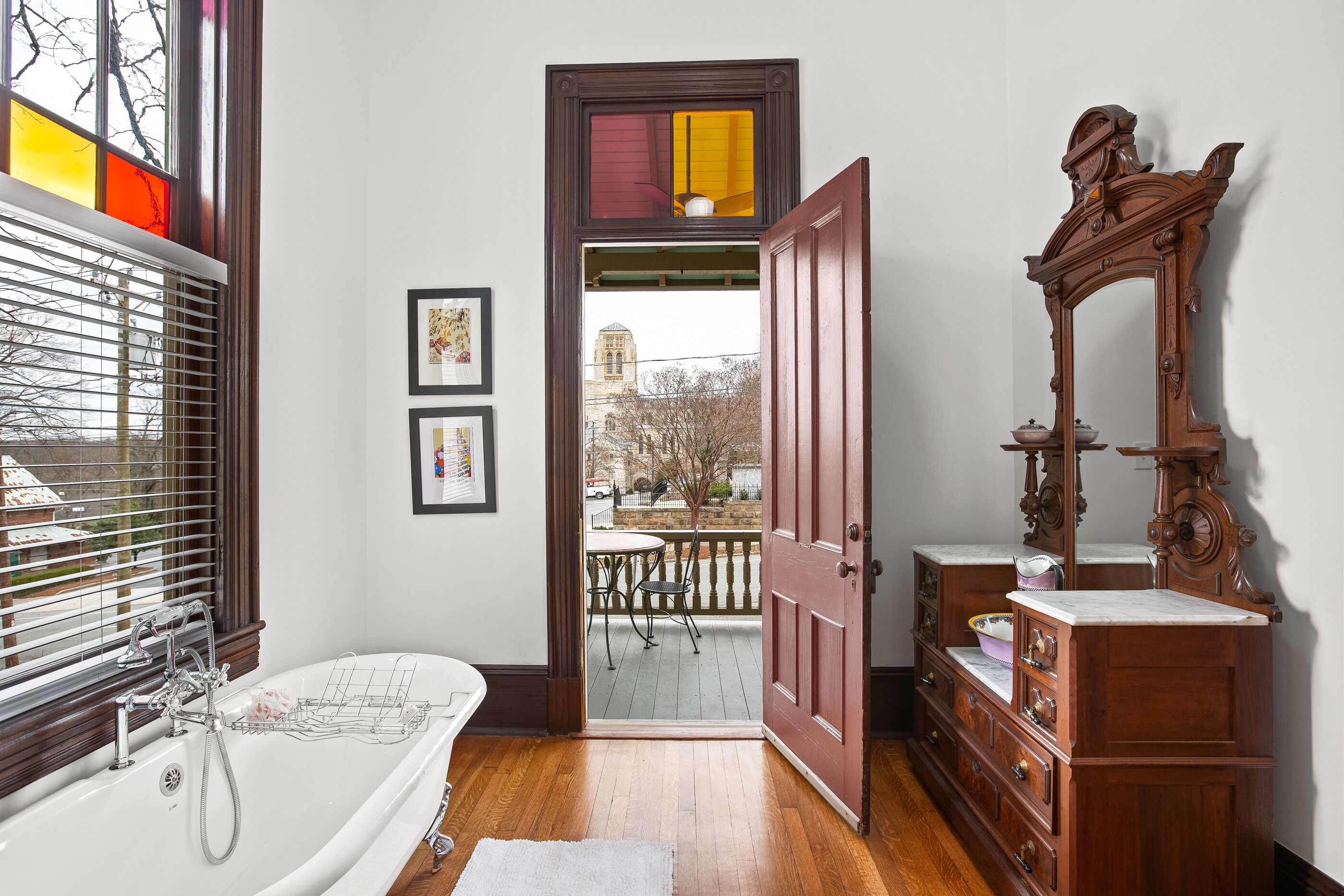 A bathroom with a bathtub, a wooden dresser, and a large mirror.