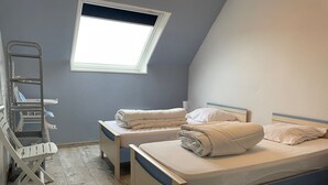 A bedroom with two beds, a window, and a wheelchair. - Charming sea house (Saint-Valery-en-Caux)