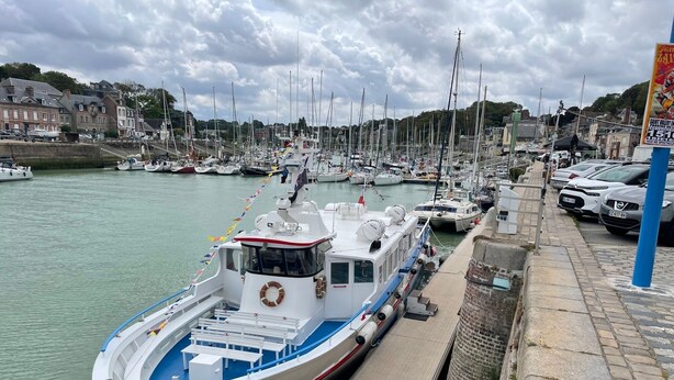A harbor with a docked boat, a stone walkway, and a row of parked cars. - Charming sea house (Saint-Valery-en-Caux)
