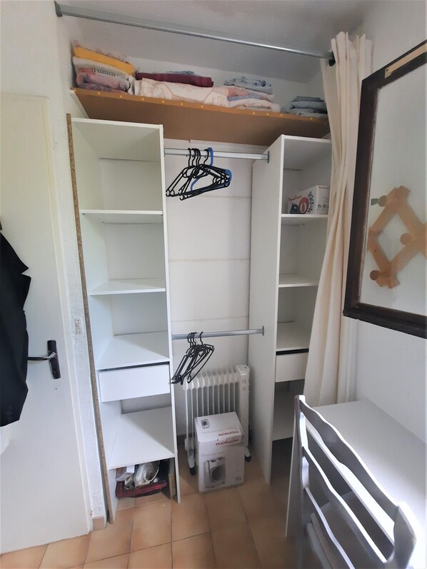 Una habitación compacta con armario empotrado, un radiador y un pequeño calentador.