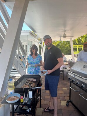 An outdoor barbecue area with a grill, a table with food, and a covered seating area. - PALM COTTAGE - Sleeps 4  summer fun ..lobster season.   (Summerland Key)