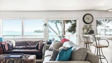 A living room with a sofa, ottoman, and a dining area with chairs and a table.