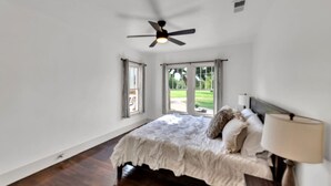 A bedroom with a bed, a ceiling fan, and large windows. - Charming, Tudor Style Home Newly Renovated! (Mineral Wells)