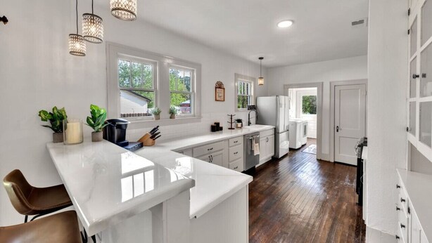 A modern kitchen with white cabinetry, a marble countertop, and pendant lighting. - Charming, Tudor Style Home Newly Renovated! (Mineral Wells)