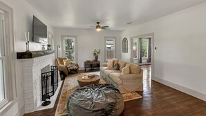 A spacious living room with a fireplace, a ceiling fan, and a large bean bag chair. - Charming, Tudor Style Home Newly Renovated! (Mineral Wells)