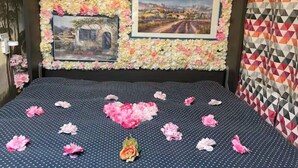A bed with a floral headboard, two framed pictures, and a polka dot bedspread. - Charming, private studio (Paris)