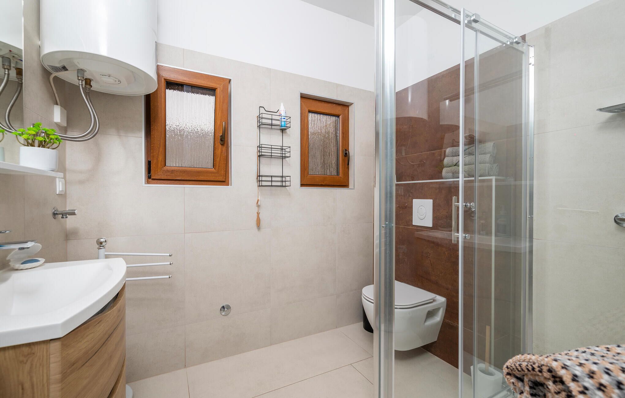 Une salle de bain moderne avec une douche à parois de verre, des toilettes et un lavabo avec un meuble-vasque en bois.