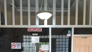 Un mostrador de recepción con un cartel de 'No Entrar', un cartel de 'No Fumar' y un cartel que dice 'Recepción' encima.