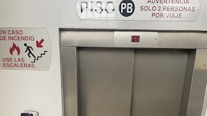 Un ascensor con un cartel que indica que es una salida de emergencia por incendio y una ocupación máxima de dos personas.