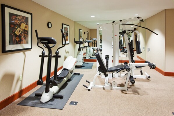 A gym with exercise equipment, a clock, and a framed picture on the wall.