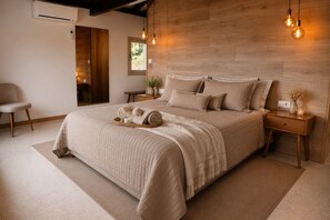 A bedroom with a large bed, bedside tables, a chair, and a wooden headboard. - Casa da Montanha_Casas Vale do Lima Group (Arcos de Valdevez)