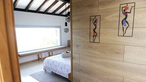 A bedroom with a bed, a window, and wooden wall panels.