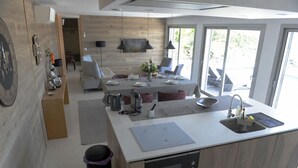 A modern kitchen with a built-in oven, a dining area with a table set for four, and a large window providing a view of the outdoors.