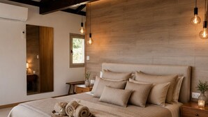 A bedroom with a large bed, wooden ceiling beams, and pendant lighting. - Casa da Montanha_Grupo Casas Vale do Lima (Arcos de Valdevez)