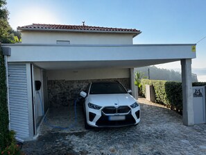 Een witte auto geparkeerd in een overdekte garage met een stenen muur en een betegeld dak.