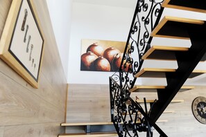 A staircase with a metal railing, wooden steps, and a wall-mounted clock.