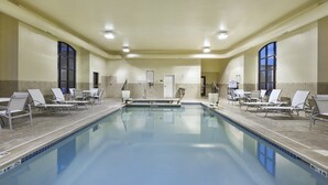 A large indoor swimming pool with lounge chairs and a changing room.