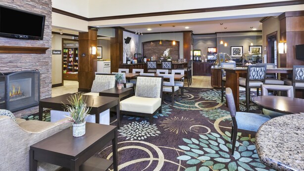 A hotel lobby with a fireplace, seating area, and a bar.