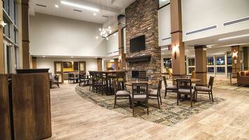 A spacious lobby with a stone fireplace, multiple seating areas, and a large screen.