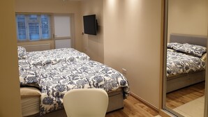 A bedroom with a bed, a chair, a TV, and a mirror.