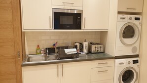 A compact kitchen with a microwave, toaster, and washing machine.