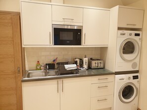 Compact kitchen with a sink, faucet, microwave, washing machine, and toaster.