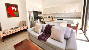 A modern living room with a sofa, a bench, and a kitchen in the background. - Brand New! Jaco Beach outside the back gate! (Jaco)