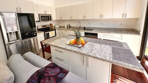 A modern kitchen with white cabinets, stainless steel appliances, and a granite countertop. - Brand New! Jaco Beach outside the back gate! (Jaco)