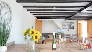 Un coin repas avec une table en bois, une horloge et un vase rempli de tournesols.