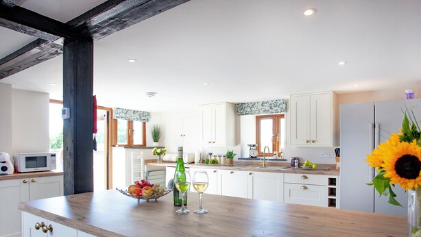 Une cuisine moderne avec des meubles blancs, un plan de travail en bois et un évier encastré.