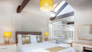Une chambre d’hôtel avec un lit superposé, une table de chevet avec des lampes, un miroir et un banc en bois.