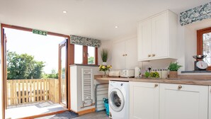 Une cuisine moderne équipée d’un lave-linge, d’un grille-pain et d’une balance posée sur le plan de travail.