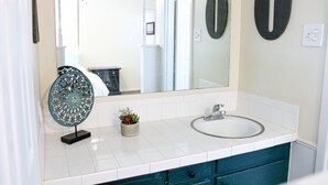 Un bagno con un lavandino bianco, uno specchio e un elemento decorativo in metallo sul piano di lavoro.