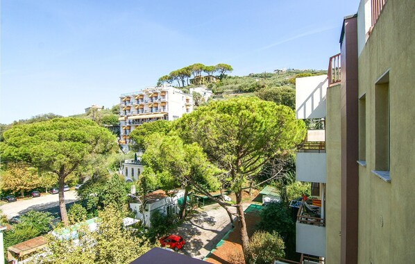 Un quartier résidentiel avec un immeuble à plusieurs étages, des arbres et des voitures garées.