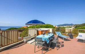 A terrace with a table, chairs, a blue umbrella, and a view of the sea. - Beautiful apartment in Lavagna with WiFi (Lavagna)