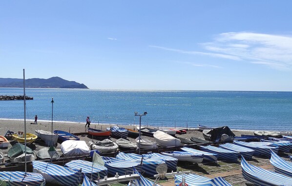 A beach with rows of striped beach umbrellas and boats lined up on the sand. - Beautiful apartment in Lavagna with WiFi (Lavagna)