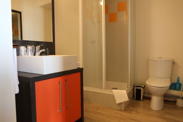 A bathroom with a sink, mirror, shower, and toilet.