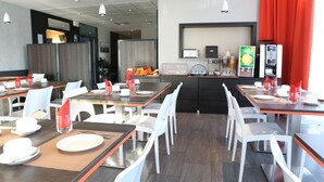 A modern dining area with multiple tables and chairs, a coffee machine, and a counter with a beverage dispenser. - Retraite Modern 10 min de l'Aéroport|WIFI Inclus! (CHEVILLY LARUE)