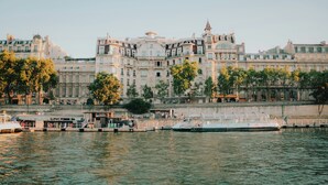 A waterfront hotel with a large building, a dock with boats, and a river. - Retraite Modern 10 min de l'Aéroport|WIFI Inclus! (CHEVILLY LARUE)