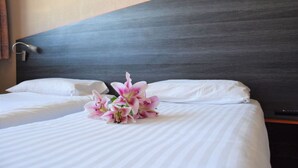 A hotel room with two beds, white linens, a dark headboard, and a bouquet of pink flowers on the bed. - Près de Paris | Studio Modern (CHEVILLY LARUE)