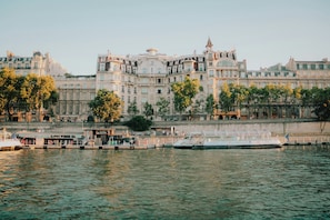A waterfront hotel with a large building, a dock with boats, and a river.