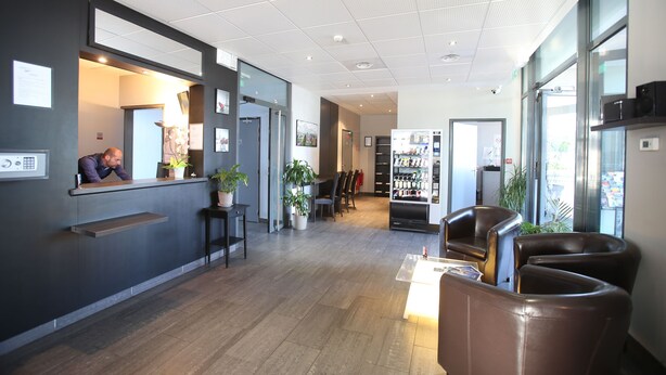 A modern hotel lobby with a reception desk, seating area, and a vending machine.
