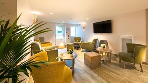 Ein modernes Wohnzimmer mit gelbgrünen Polstersesseln, einem runden Couchtisch und einem flachbildfernseher, der an der Wand befestigt ist.
