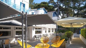 Ein Außenbereich mit Terrasse, gelben Stühlen, Tischen und Sonnenschirmen.