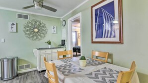 A dining area with a table set for four, a ceiling fan, a decorative wall piece, and a framed picture. - Pet-Friendly Taylor Home w/ Backyard Oasis! (Taylor)