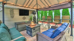 A covered patio with a fire feature, outdoor furniture, and a TV mounted on the wall. - Pet-Friendly Taylor Home w/ Backyard Oasis! (Taylor)