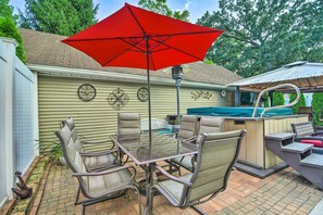 Un patio con una mesa y sillas de vidrio, una sombrilla roja y una zona de barbacoa.