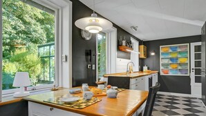 A modern kitchen with a wooden countertop, a built-in sink, and a large window overlooking greenery. - 5 bedroom awesome home in Erslev (Erslev)