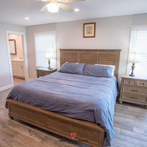 Un dormitorio con cama de madera, una mesita de noche, un aparador y un ventilador de techo.
